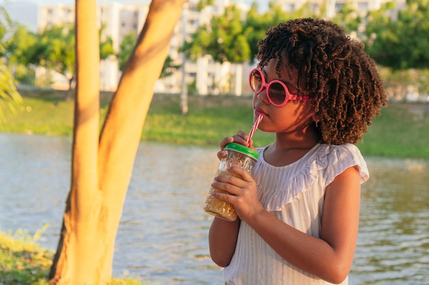 Chica bebiendo un jugo en el parque