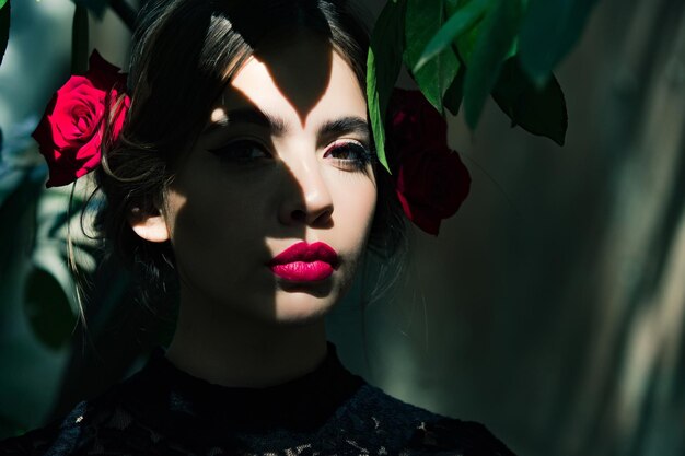 Chica de belleza con labios rojos y rosas en cabello moreno