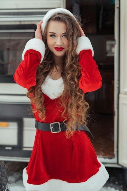 Chica de belleza en traje de santa en el campamento de invierno preparándose para la celebración del año nuevo