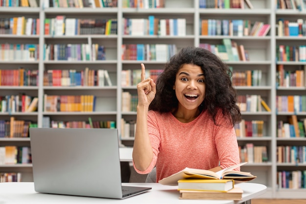 Foto chica en biblioteca señalando