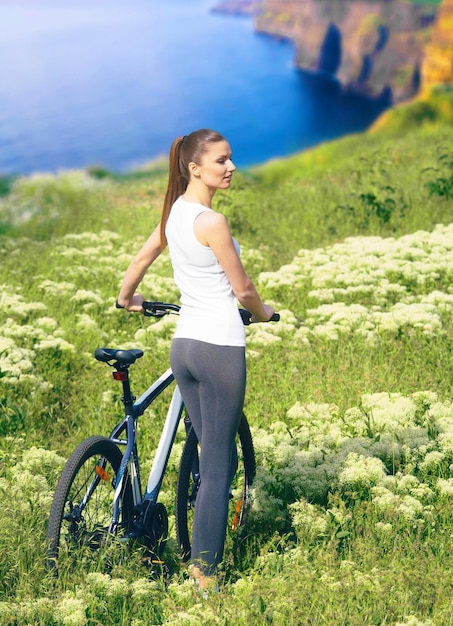 Chica con bicicleta caminando por el campo