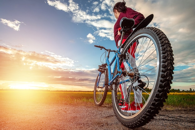 Chica en bicicleta en el fondo del atardecer