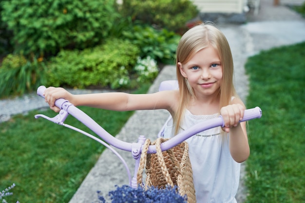 Chica con bicicleta y lavanda en verano en el patio