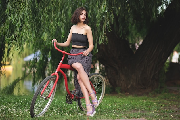 Chica con una bicicleta Modelo encantador posando junto a la bicicleta retro roja