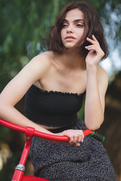 Chica con una bicicleta Modelo encantador posando junto a la bicicleta retro roja