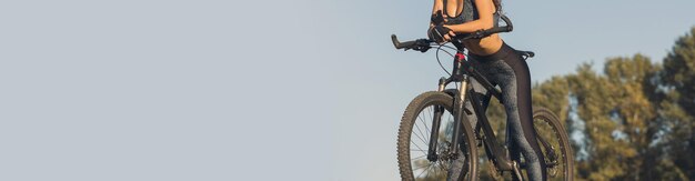 Foto chica en bicicleta de montaña en campo a través hermoso retrato de un ciclista al atardecer chica fitness monta una bicicleta de montaña moderna de fibra de carbono en ropa deportiva retrato de una niña con casco y gafas