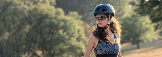 Foto chica en bicicleta de montaña en campo a través hermoso retrato de un ciclista al atardecer chica fitness monta una bicicleta de montaña moderna de fibra de carbono en ropa deportiva retrato de una niña con casco y gafas