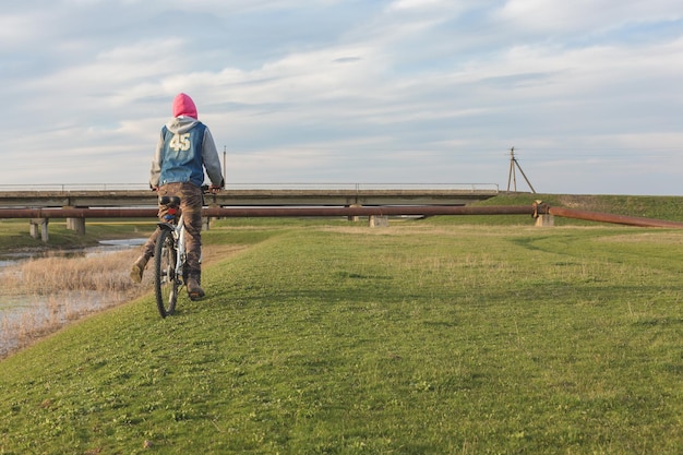 Chica en bicicleta de montaña en campo a través hermoso retrato de un ciclista al atardecer Chica fitness monta una bicicleta de montaña moderna de fibra de carbono en ropa deportiva Retrato de una niña con casco y gafas