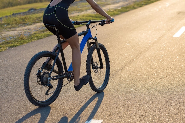 Chica en bicicleta de montaña en campo a través hermoso retrato de un ciclista al atardecer Chica fitness monta una bicicleta de montaña moderna de fibra de carbono en ropa deportiva