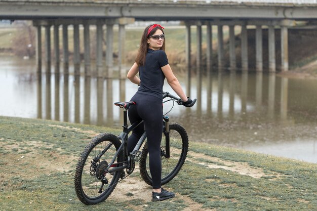 Chica en una bicicleta de montaña en offroad hermoso retrato de un ciclista en tiempo lluvioso