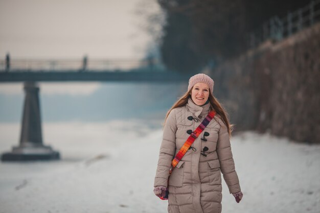 Chica bien vestida caminando sobre el río helado en invierno