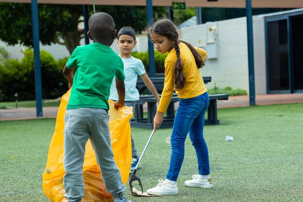 Una chica biracial con una camiseta amarilla recogiendo basura con un chico afroamericano de verde