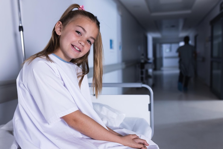 Foto una chica blanca feliz sentada en la cama en el pasillo del hospital con espacio para copiar