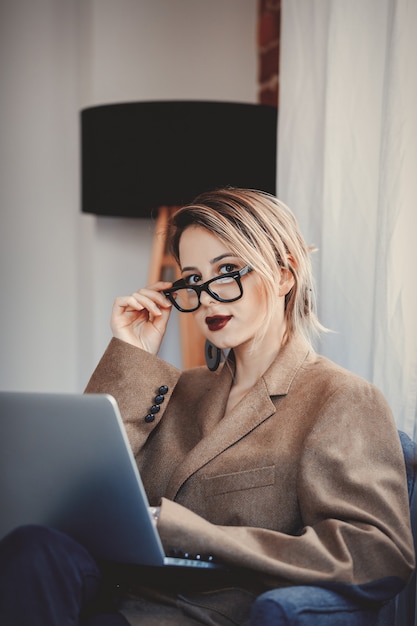 Chica en blazer y gafas trabajando con computadora portátil