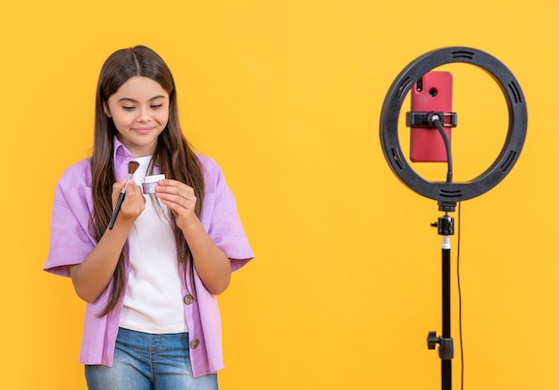 Chica blogger adolescente con polvo aislado en espacio de copia amarilla chica blogger adolescente con cepillo