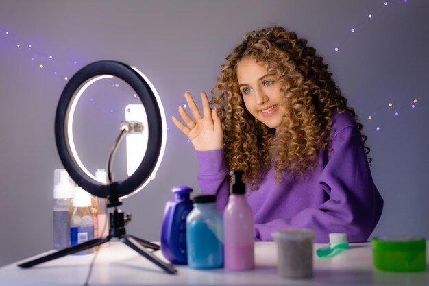 Chica bloguera de belleza está transmitiendo en vivo desde su teléfono inteligente y haciendo una revisión de cosméticos