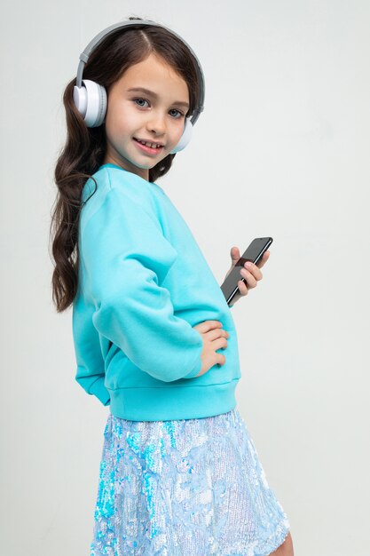 Chica en una blusa azul se relaja con música en auriculares grandes y elegantes