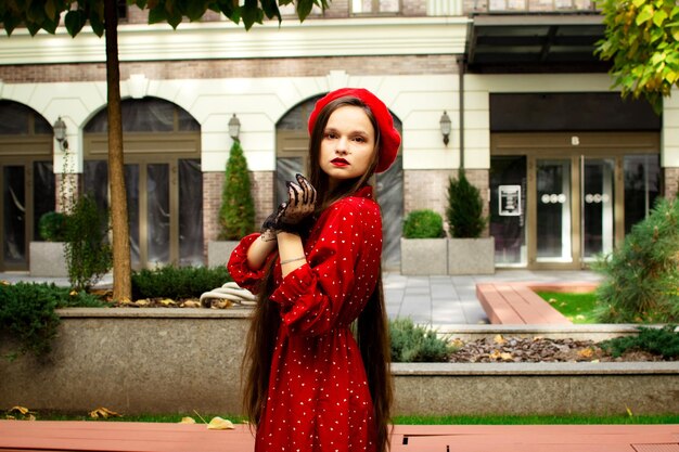 Una chica con una boina roja camina en la ciudad de otoño.