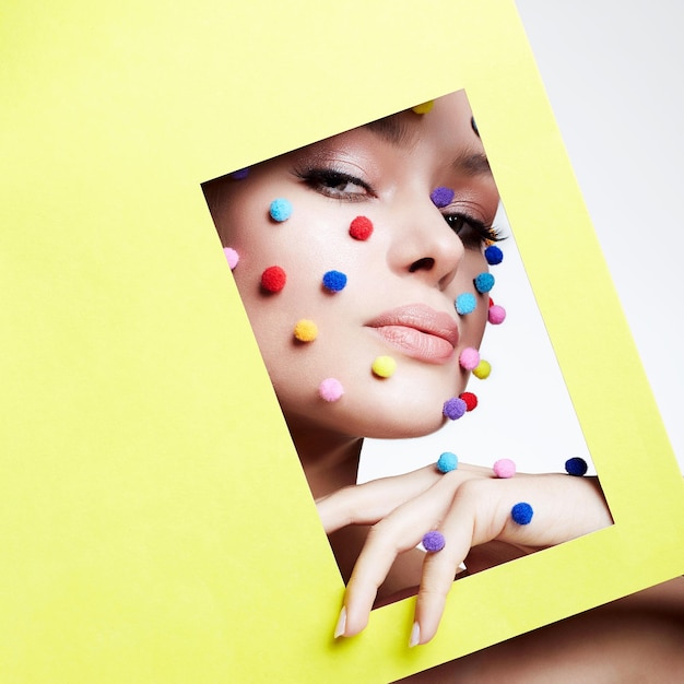 Chica con bolas de colores en el concepto de maquillaje de su cara