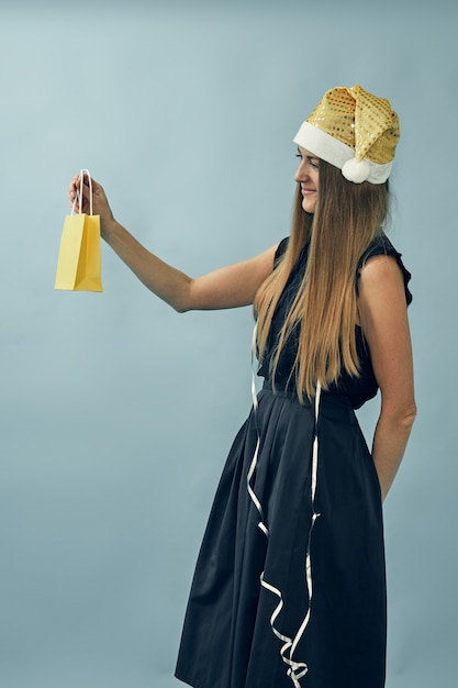 Chica con una bolsa de regalo en sus manos y con un sombrero de santa claus