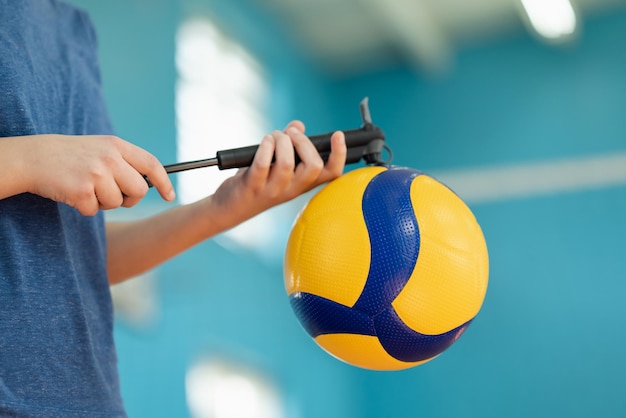 Chica bombeando pelota de voleibol con bomba de mano de cerca Pelota profesional para jugar voleibol en la cancha preparación para el entrenamiento