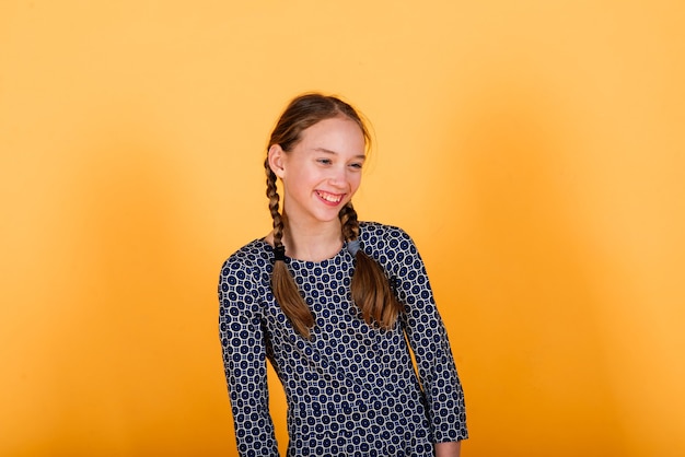 Chica bonita adolescente sonriendo a la cámara mirando alegre sobre fondo amarillo. Emociones positivas