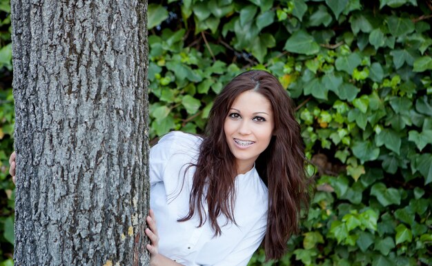 Chica bonita morena junto a un árbol