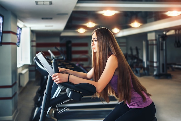 Chica bonita de pelo largo entrenando en el gimnasio