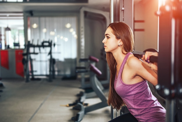 Chica bonita de pelo largo entrenando en el gimnasio