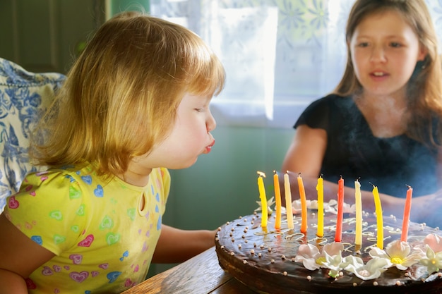 Chica bonita que sopla las velas en la torta