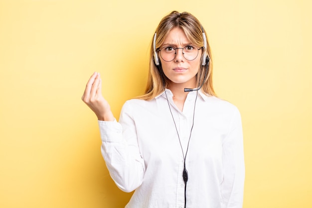 Chica bonita rubia haciendo gesto de capice o dinero, diciéndole que pague. concepto de auricular