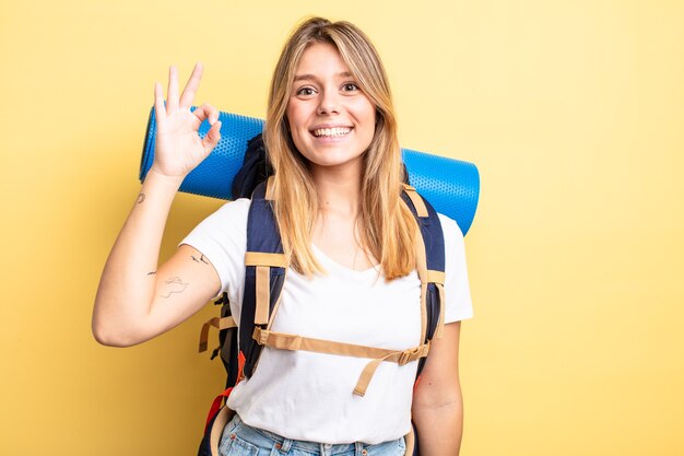 Chica bonita rubia que se siente feliz, mostrando aprobación con gesto bien. concepto de excursionista