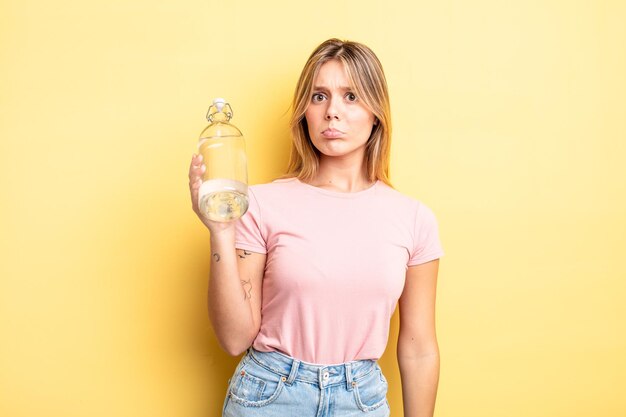 Chica bonita rubia que se siente triste y llorona con una mirada infeliz y llorando. concepto de botella de agua