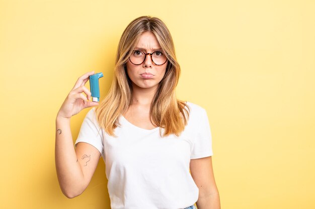 Chica bonita rubia que se siente triste y llorona con una mirada infeliz y llorando. concepto de inhalador para el asma