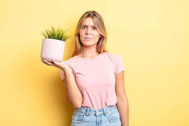 Chica bonita rubia que se siente triste, molesta o enojada y mirando hacia un lado. concepto de planta de interior