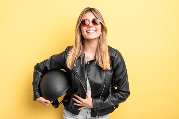 Chica bonita rubia riendo a carcajadas de una broma hilarante. concepto de casco de moto