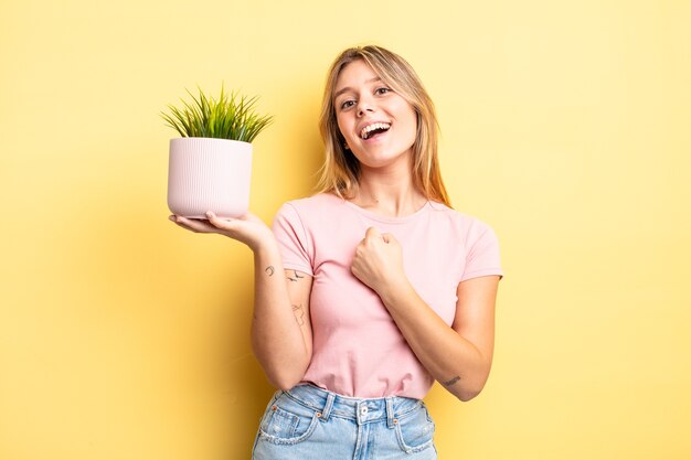 Chica bonita rubia sintiéndose feliz y enfrentando un desafío o celebrando. concepto de planta de interior