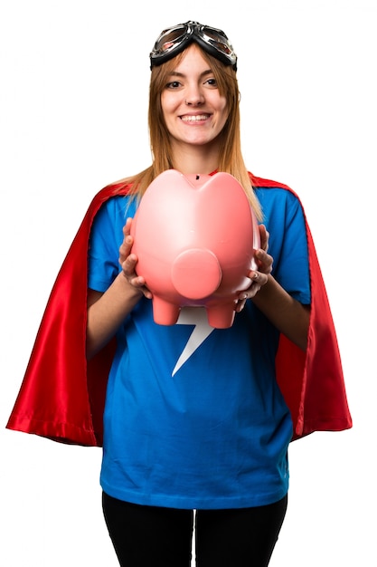 Chica bonita superhéroe sosteniendo un piggybank