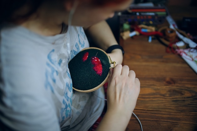 Foto chica está bordando gorro de hongo en tela verde hecho a mano artesanía hobby mujer cosiendo hilo dental con hilo ...