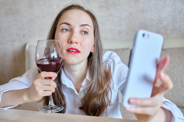 Foto chica borracha con una copa de vino toma una foto selfie.