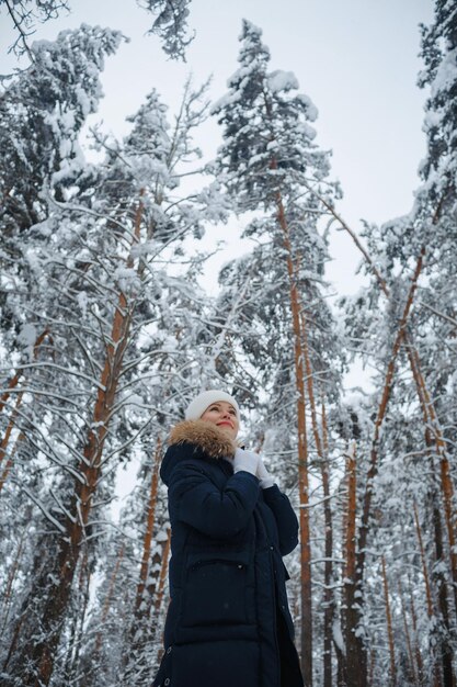 Una chica en un bosque de invierno, rubia, un divertido paseo por la naturaleza.