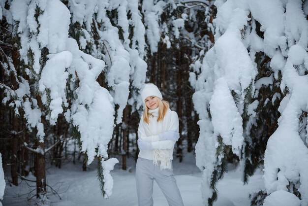 Una chica en un bosque de invierno, rubia, un divertido paseo por la naturaleza.