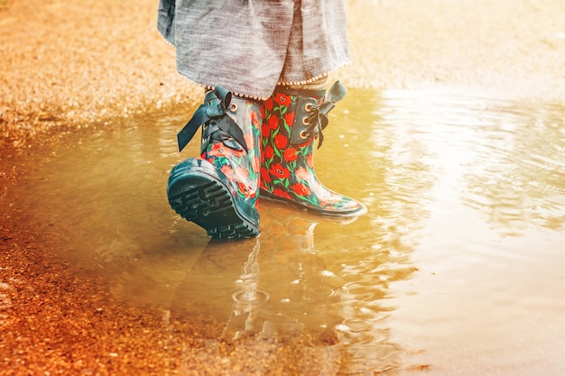 Foto chica en botas de lluvia está de pie en un charco