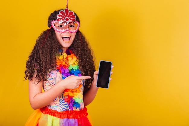 Chica brasileña caucásica vestida para el carnaval apuntando a la aplicación de pantalla móvil mundo conectado