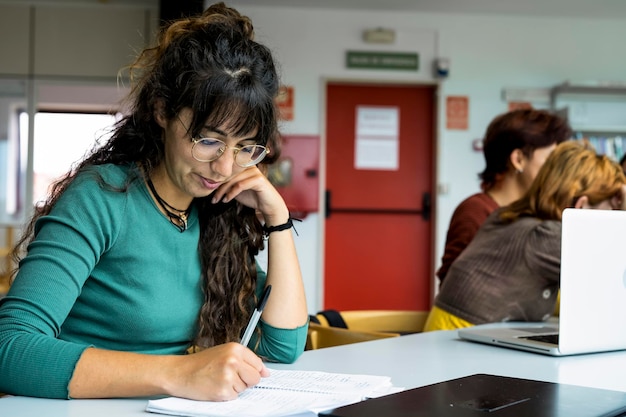 Chica bronceada joven que estudia en una biblioteca