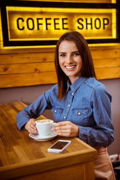 Foto chica en un buen café bebe delicioso café.