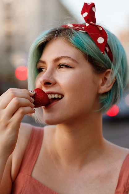 Chica con cabello azul come fresas en el verano