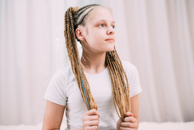 Chica con cabello castaño y coletas trenzadas con cabello artificial