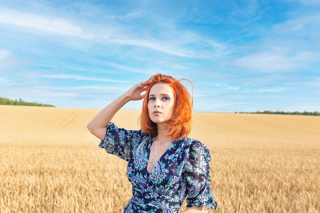 Una chica con un cabello hermoso de pie en medio de un campo de trigo.