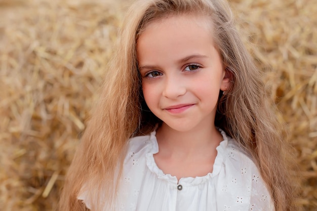 una chica con cabello largo y ojos grandes con un vestido blanco en un campo de trigo